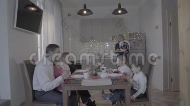 可爱快乐的四个孩子一家人庆祝新年厨房餐桌父亲儿子女儿微笑的母亲端饭
